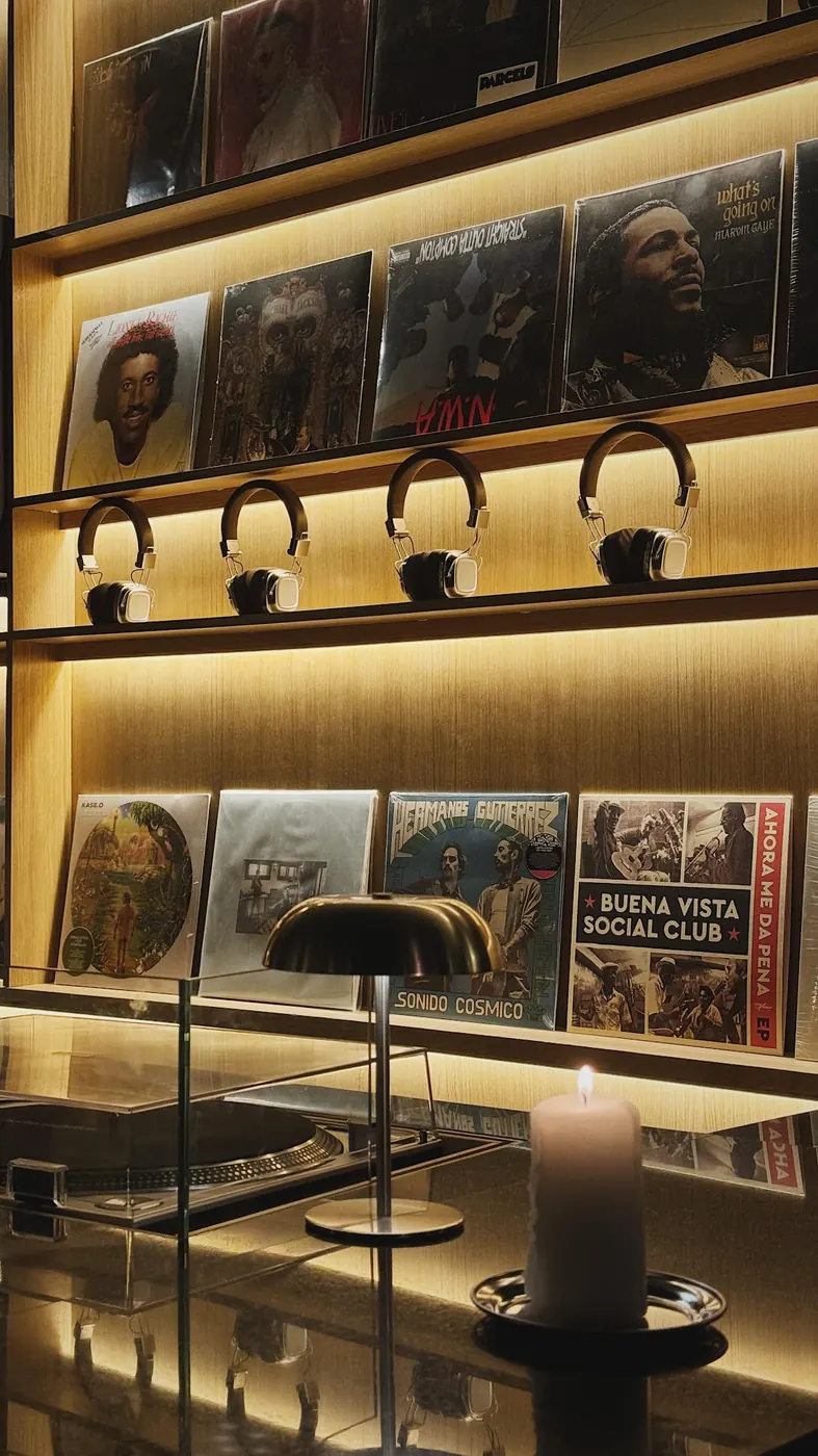 Pared de vinilos de Gastón con auriculares y una vela encendida: Marvin Gaye, Buena Vista Social Club, Hermanos Gutiérrez